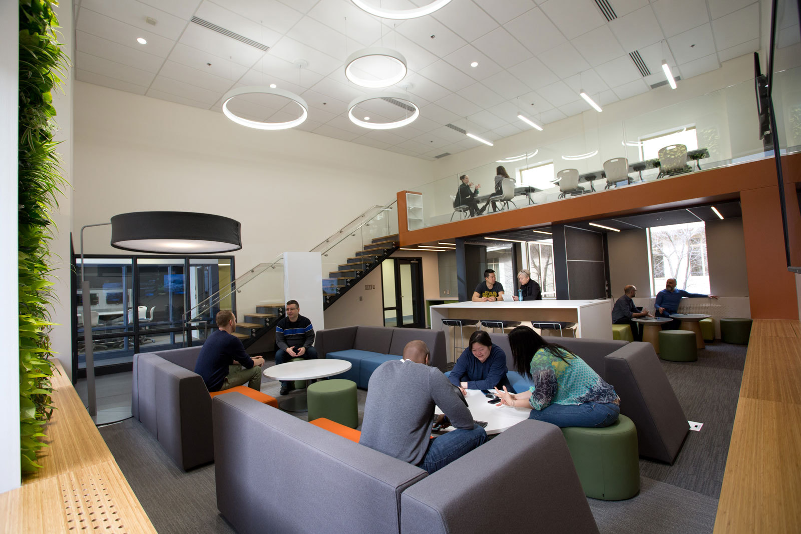 The room is an open space with a balcony above half of the room. It has tables and armchairs.